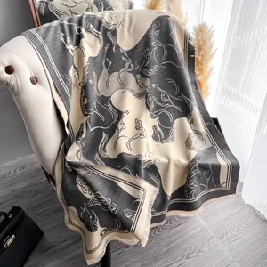Dettaglio di sciarpa in cashmere grigio e beige con motivo jacquard di cavalli e frange
