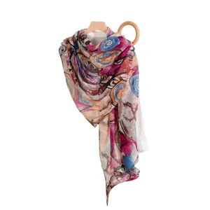 Artistic abstract print silk scarf with vibrant colors displayed on a wooden hanger