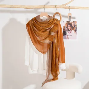 Sciarpa leggera a righe sfumate arancio e beige esposta su un supporto di legno