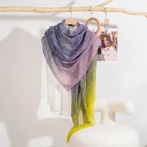 Elegante scialle con stampa paisley sfumata blu e gialla appeso a un supporto in legno