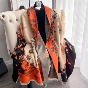 Dettaglio di sciarpa color-block con motivi floreali e frange corte su sedia beige