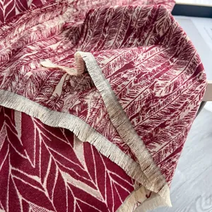 Dettaglio ravvicinato della sciarpa jacquard bordeaux con trama geometrica e frange