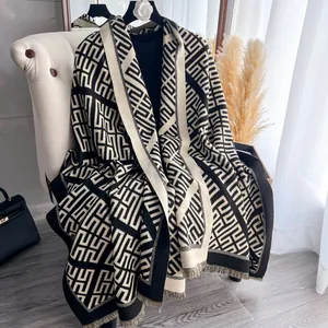 Dettaglio ravvicinato di uno scialle in maglia geometrica con frange in nero e beige