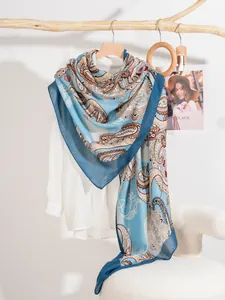 Dettaglio di uno scialle blu con motivo paisley appeso a un appendiabiti rustico
