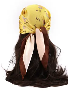 Rear view of a model wearing a floral yellow satin scarf tied in a bow on wavy hair