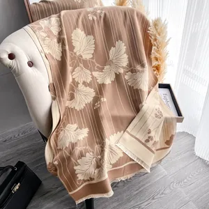 Dettaglio dello scialle jacquard floreale con frange su tessuto pashmina color cammello