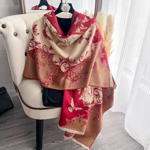 Dettaglio della sciarpa invernale bicolore con motivi floreali jacquard e frange