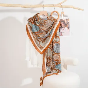 Elegante sciarpa paisley marrone caramello e blu, drappeggiata su camicia bianca