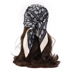 Black and white paisley print faux silk scarf tied on long wavy hair in a back view