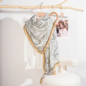 Scialle in seta bianca con motivo paisley e bordo dorato su supporto in legno