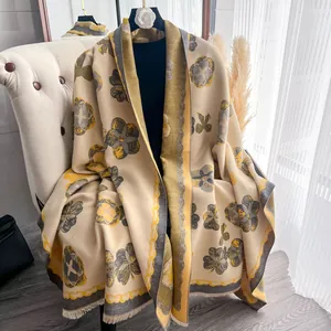 Détail du châle effet cachemire beige avec motifs floraux jaunes et bordures à franges