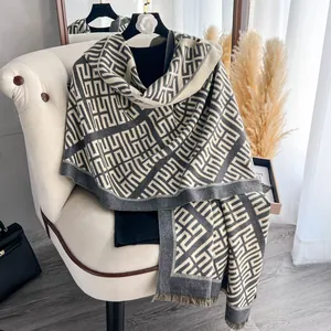Dettaglio di scialle grigio effetto cashmere con motivo geometrico e frange eleganti