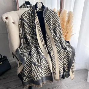Dettaglio della sciarpa in maglia spessa con motivi geometrici e frange
