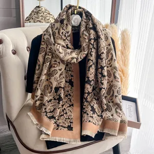 Dettaglio di sciarpa paisley beige e nera con eleganti frange lungo il bordo