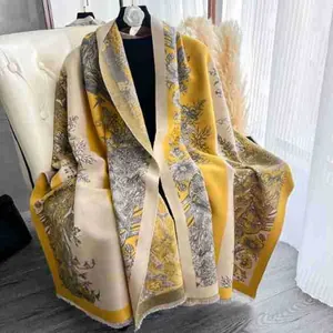 Detail of yellow floral cashmere shawl with tassel edges draped on a white sofa