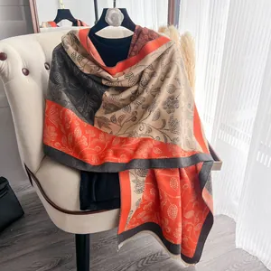 Detail of floral patterns and fringe on a thick orange and beige cashmere pashmina shawl
