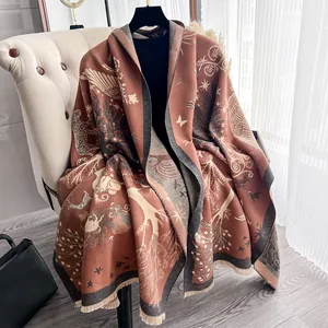 Scialle spesso effetto cashmere con motivi a foresta e nappe su poltrona in pelle di lusso