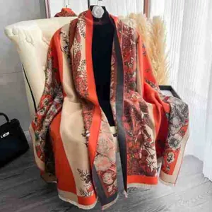 Detail of floral print shawl with vintage orange and beige patterns and frayed edges