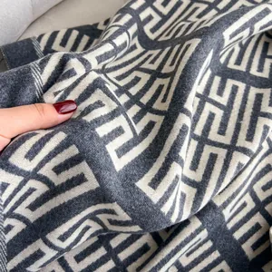 Dettaglio della sciarpa in finto cashmere grigio con motivo geometrico e mano soffice
