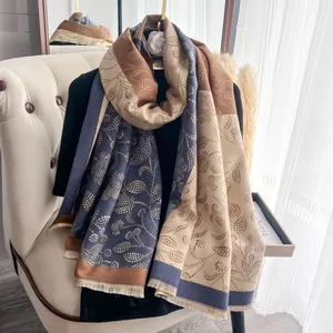 Detail of navy and tan floral scarf with fine fringe on a beige armchair background