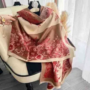 Detail of red floral toile de jouy pattern on beige fringe scarf over sofa