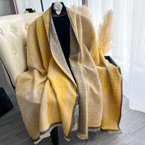 Dettaglio dello scialle pashmina giallo con motivo paisley vintage e bordi a frange