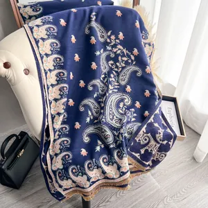 Detailed close-up of dark blue paisley scarf with tassels draped on a sofa