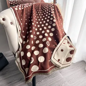 Dettaglio di sciarpa in maglia spessa con pois e camelia e frange su una sedia