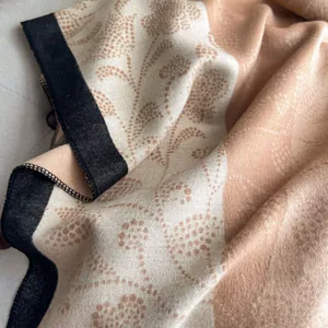 Detailed macro shot showing woven texture and beige floral patterns on a thick winter scarf