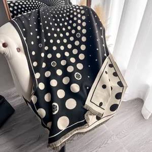Dettaglio dello scialle spesso in cashmere a pois e motivo camelia con frange corte