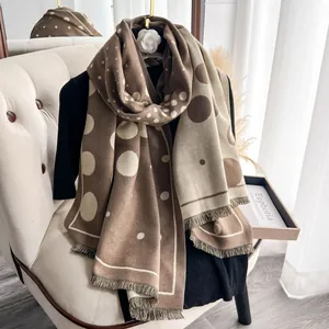 Dettaglio della sciarpa a pois marrone e beige con trama tipo cashmere e frange corte