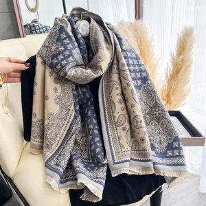 Scialle pashmina blu navy e beige con motivo paisley e frange su una sedia bianca elegante