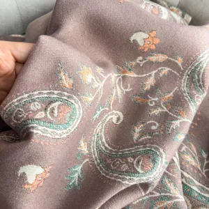 Detail of soft paisley pattern scarf in dusty rose featuring intricate woven texture