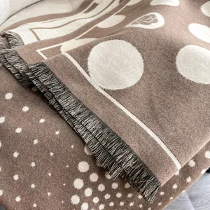Dettaglio del motivo a pois double-face e delle morbide frange su questa sciarpa di cashmere