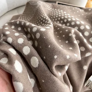 Dettaglio di una spessa sciarpa color caffè con pois bianchi e trama in finto cashmere