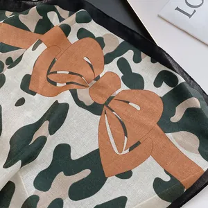 Détail du nœud imprimé léopard et texture camouflage sur écharpe en coton avec bord noir