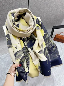 Dettaglio scialle floreale effetto cashmere con foglie blu e gialle e bordi a frange
