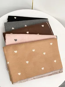 Dettaglio di sciarpe effetto cashmere con motivo a cuore jacquard e bordi con frange multicolore