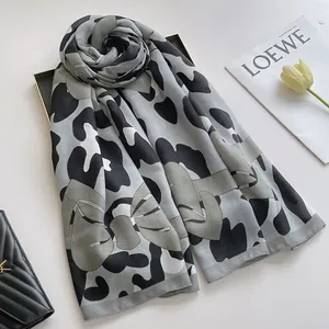 Détail du motif léopard et nœud sur un châle en lin et coton gris et noir élégant