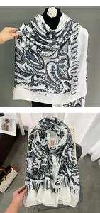 Dettaglio di sciarpa bianca in cotone e lino con motivo paisley nero e bordo etnico