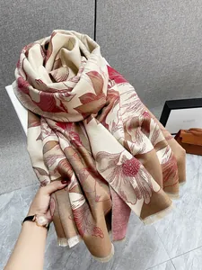 Dettaglio del motivo floreale e dei bordi sfrangiati sullo scialle beige effetto cashmere