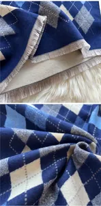 Detail of checkered cashmere scarf featuring soft tassels and blue geometric pattern