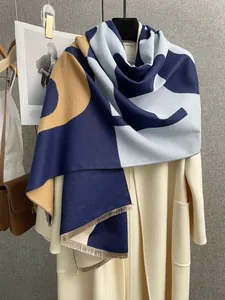 Dettaglio di sciarpa color-block con nappe abbinata a un cappotto di lana bianco crema