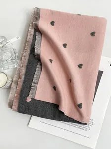 Dettaglio della sciarpa in cashmere rosa e grigio con motivi a cuore e frange