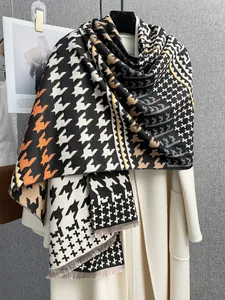 Dettaglio della trama della sciarpa pied de poule con motivi geometrici arancio e beige