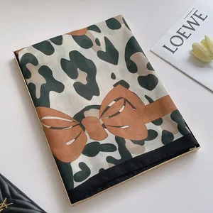 Détail de l'écharpe léopard avec nœud orange présentée dans un coffret cadeau de luxe