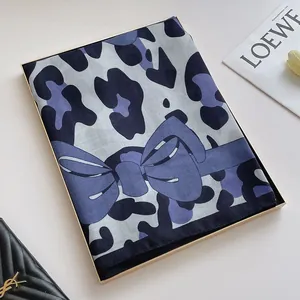 Détail d'une écharpe pliée à motif léopard et texture satinée dans un plateau doré