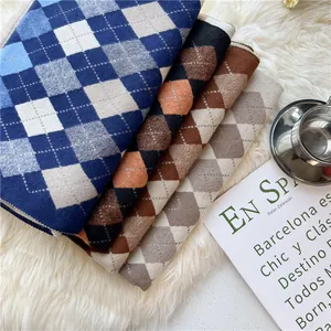 Stack of classic argyle knit scarves in blue, orange, brown and grey on a faux fur rug