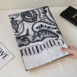 Dettaglio di sciarpa in cotone e lino con motivo paisley in una scatola regalo oro