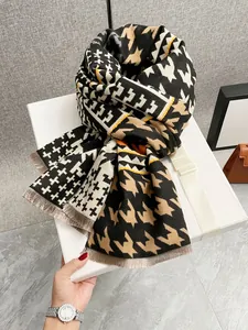 Dettaglio della sciarpa pied-de-poule con frange piegata in una scatola regalo elegante